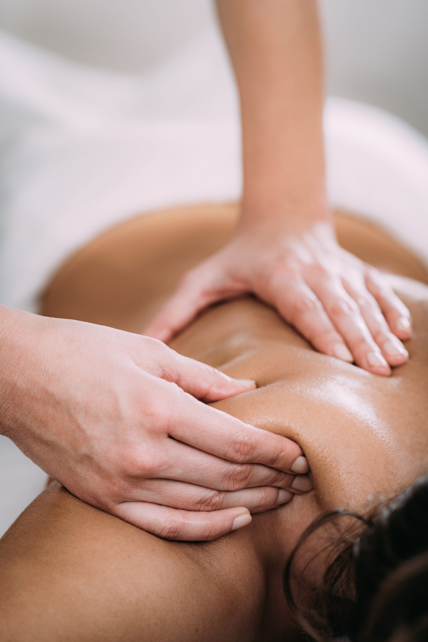 Physiotherapist massaging female patient with injured shoulder blade.  Sports injury treatment.